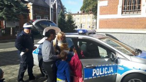 panie i dzieci oglądają policyjny radiowóz, obok którego stoją policjanci