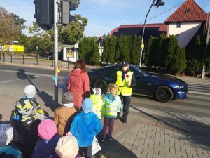 policjantka z dziećmi przy przejściu dla pieszych, w tle pojazd