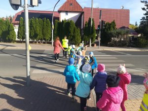 policjantka wraz z dziećmi i ich wychowawcą przechodzi przez przejście dla pieszych