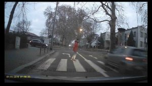 kobieta na przejściu dla pieszych, przed nią przejeżdża samochód