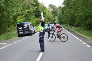 policjanci zabezpieczają wyścig kolarski obok jadą zawodnicy