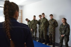 uczniowie klasy mundurowej wraz z policjantką na sali ćwiczeń