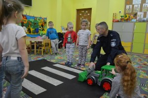 policjant uczy dzieci jak przechodzić przez jezdnię
