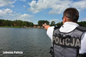 policjant kontrole jezioro z łodzi motorowej