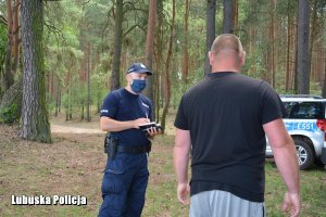 policjant rozmawia z mężczyzną w lesie, w tle radiowóz
