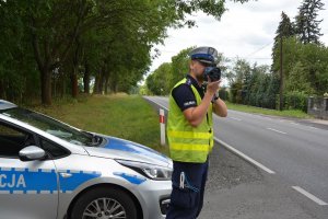 policjant urządzeniem kontroluje prędkość z jaką jadą kierowcy