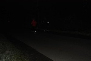osoby idące nocą, mające nałożone opaski odblaskowe