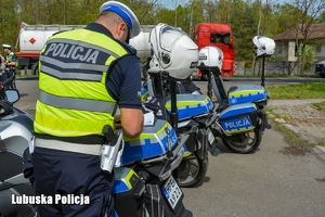 Policjant stojąc przy motocyklach sporządza dokumentację.
